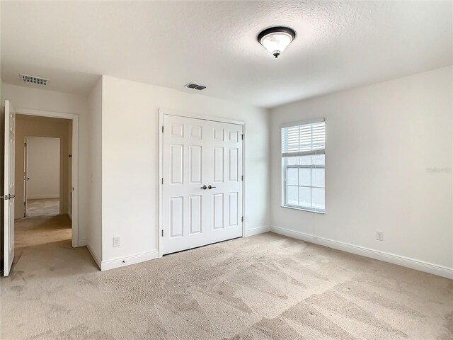 unfurnished bedroom with light colored carpet and a closet