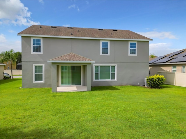 rear view of house with central AC, solar panels, and a lawn