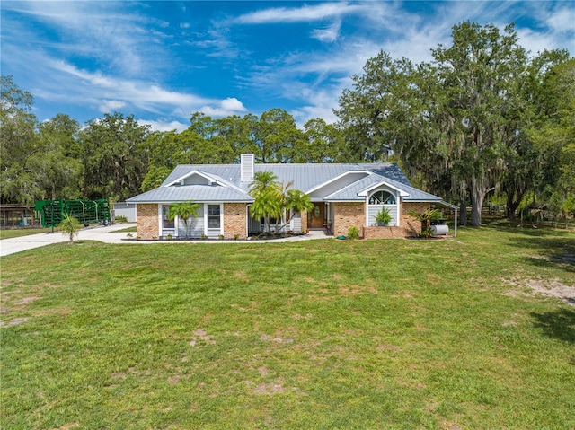 ranch-style house featuring metal roof, a chimney, a front lawn, and brick siding