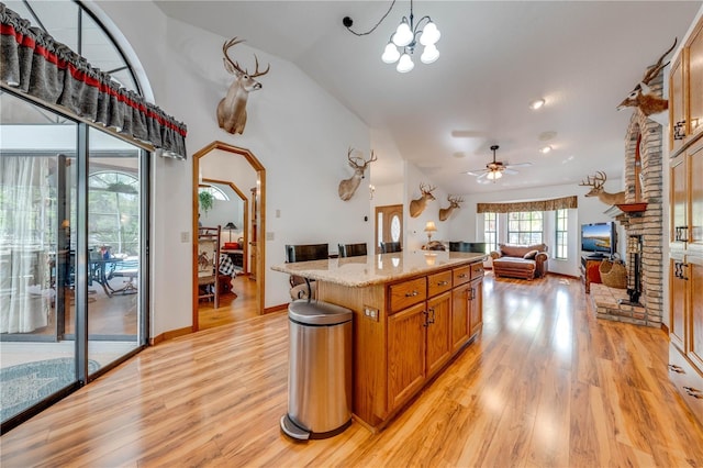 kitchen featuring a kitchen island, open floor plan, hanging light fixtures, a brick fireplace, and brown cabinetry