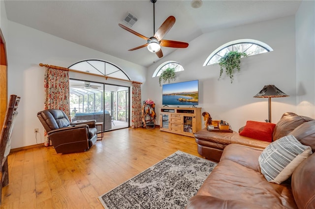 living area with high vaulted ceiling, ceiling fan, visible vents, and wood finished floors