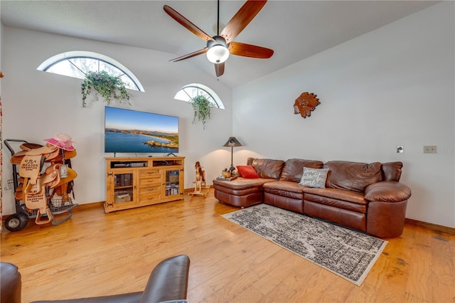 living room featuring vaulted ceiling, wood finished floors, a ceiling fan, and baseboards