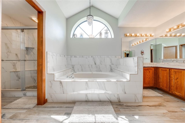 bathroom featuring shower with separate bathtub, vanity, vaulted ceiling, and wood-type flooring