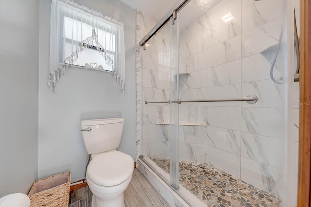 bathroom with wood-type flooring, an enclosed shower, and toilet