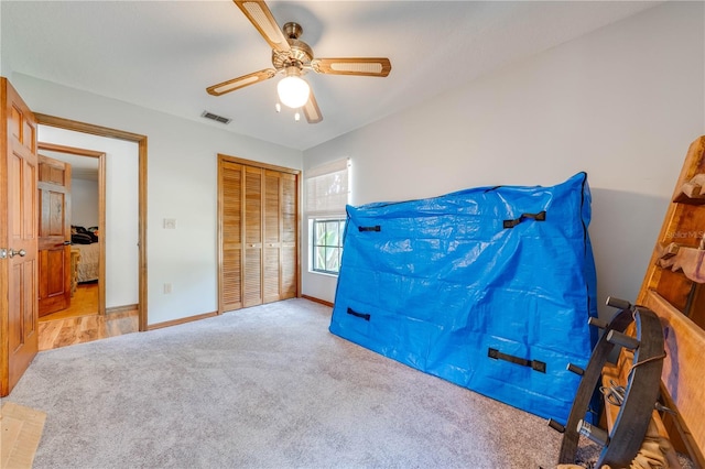 bedroom featuring baseboards, visible vents, a ceiling fan, light colored carpet, and a closet