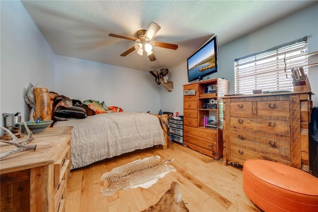 bedroom featuring ceiling fan, a textured ceiling, and wood finished floors