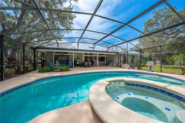 view of pool with glass enclosure, ceiling fan, an in ground hot tub, and a patio