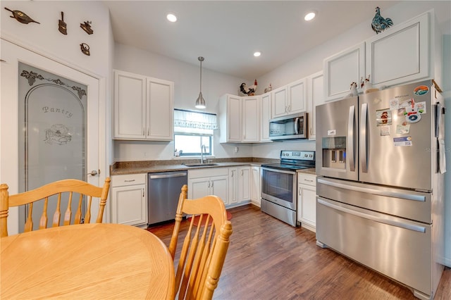 kitchen with stainless steel appliances, sink, pendant lighting, dark hardwood / wood-style floors, and white cabinetry