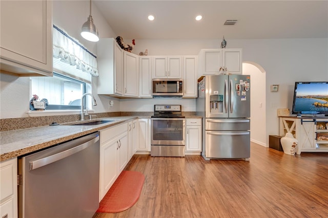 kitchen featuring white cabinetry, hanging light fixtures, and appliances with stainless steel finishes