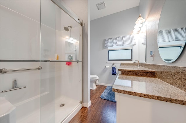 bathroom featuring toilet, a stall shower, vanity, wood finished floors, and baseboards