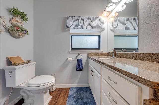 bathroom with baseboards, vanity, toilet, and wood finished floors