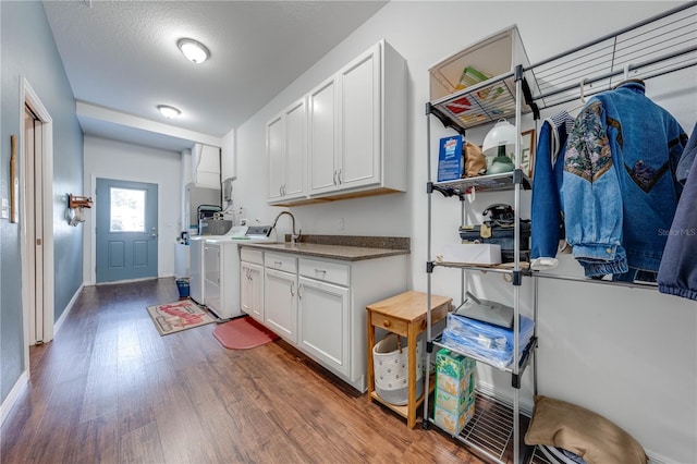 laundry area with cabinets, a textured ceiling, washing machine and dryer, and dark hardwood / wood-style floors