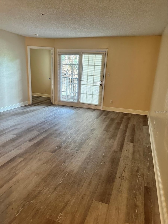 empty room with a textured ceiling and wood-type flooring