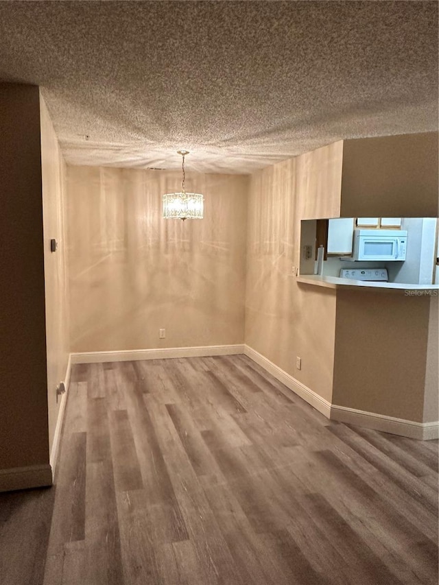 interior space with an inviting chandelier, a textured ceiling, and wood-type flooring