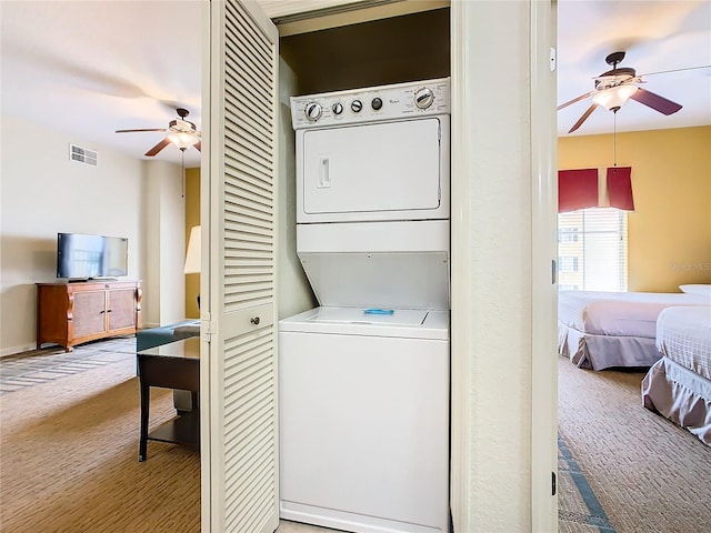 clothes washing area featuring stacked washing maching and dryer, carpet, and ceiling fan