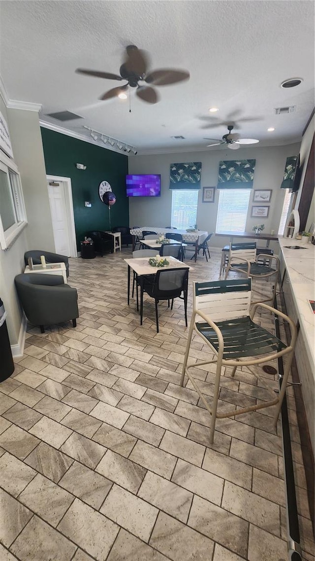 dining space with a textured ceiling, ceiling fan, and crown molding