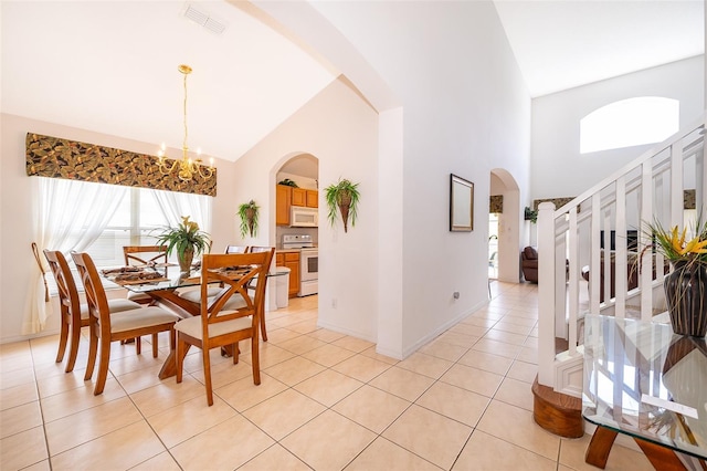 tiled dining space featuring plenty of natural light, high vaulted ceiling, and an inviting chandelier