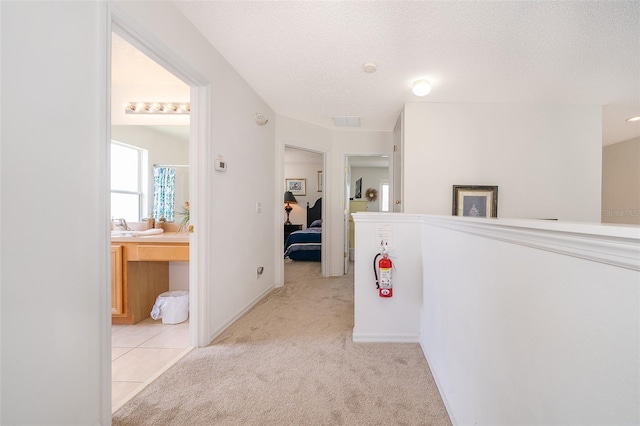 hallway featuring light carpet and a textured ceiling