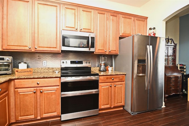 kitchen with backsplash, light stone counters, and stainless steel appliances