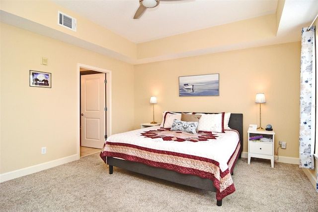 bedroom with carpet flooring, a tray ceiling, and ceiling fan