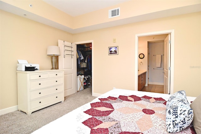 carpeted bedroom featuring a walk in closet, ensuite bathroom, and a closet