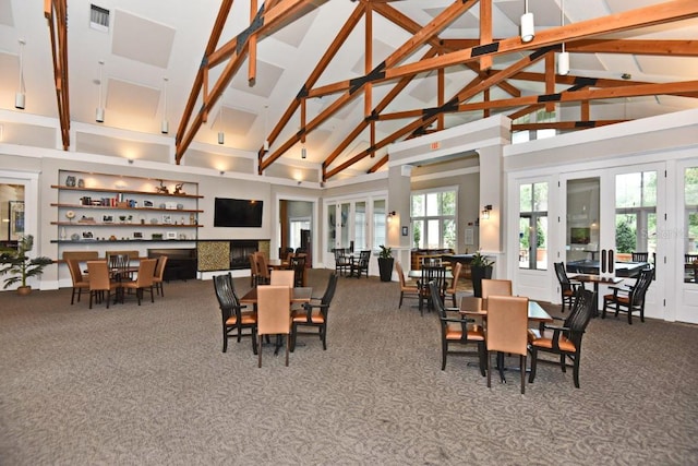 carpeted dining space with beam ceiling, a fireplace, plenty of natural light, and high vaulted ceiling