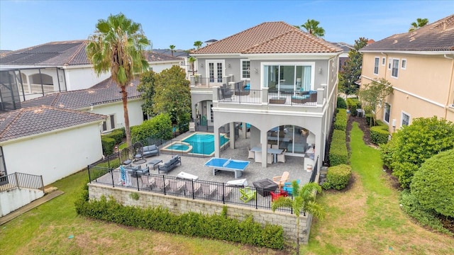 rear view of house with a lawn, a balcony, a fenced in pool, and a patio area