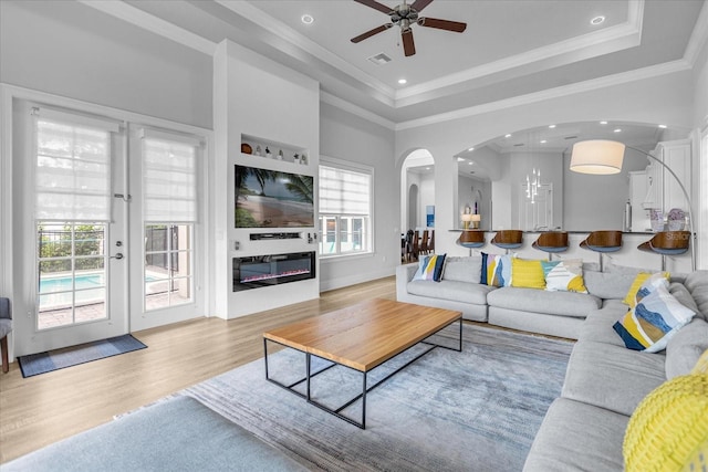 living room featuring crown molding, a wealth of natural light, and a raised ceiling