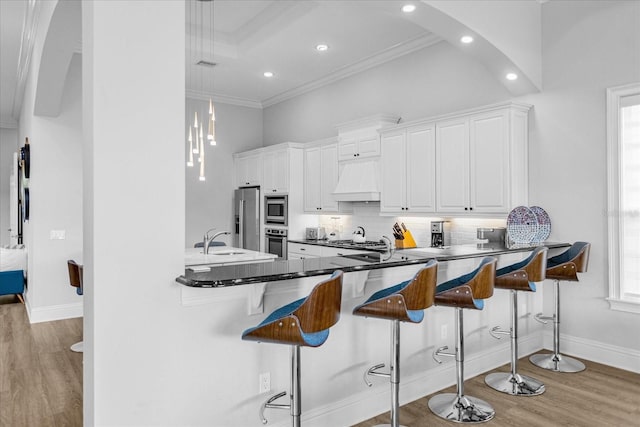 kitchen featuring white cabinetry, stainless steel appliances, a breakfast bar, and kitchen peninsula