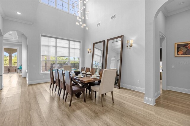 dining space with ornamental molding, light hardwood / wood-style flooring, and a high ceiling