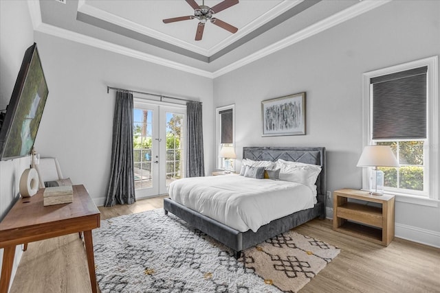 bedroom featuring access to outside, ceiling fan, a raised ceiling, crown molding, and light hardwood / wood-style flooring