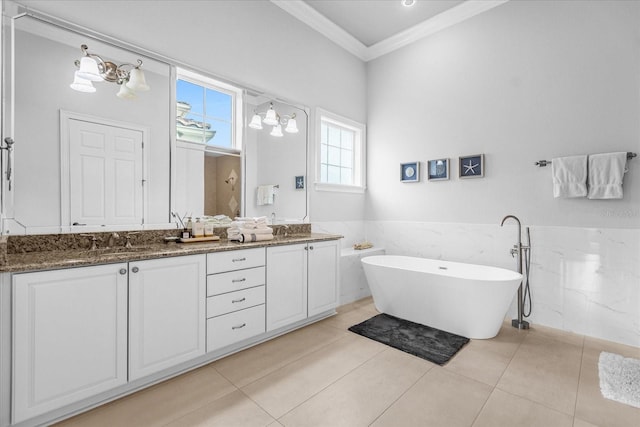 bathroom with tile walls, a tub to relax in, tile patterned flooring, vanity, and crown molding