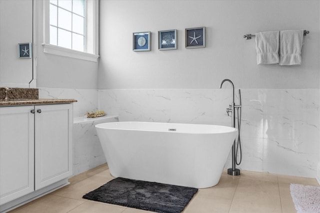 bathroom featuring vanity, a bathing tub, tile patterned flooring, and tile walls