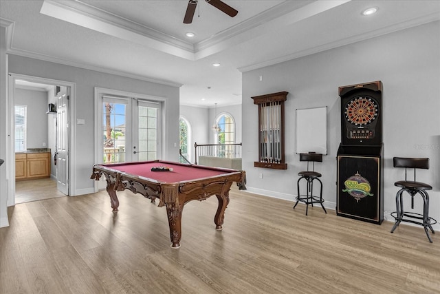 game room with french doors, ornamental molding, light hardwood / wood-style floors, and a tray ceiling