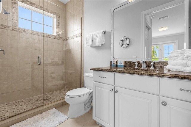 bathroom featuring tile patterned flooring, vanity, toilet, and walk in shower