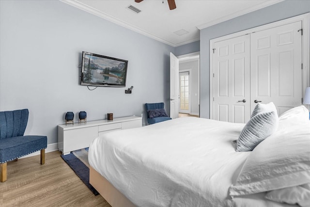 bedroom with crown molding, light hardwood / wood-style floors, ceiling fan, and a closet