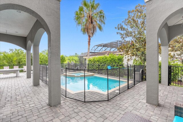 view of swimming pool featuring an in ground hot tub, glass enclosure, and a patio area