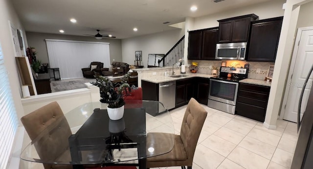 kitchen with sink, light tile patterned floors, appliances with stainless steel finishes, light stone countertops, and decorative backsplash