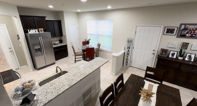 kitchen with light stone countertops, light tile patterned floors, and stainless steel fridge with ice dispenser