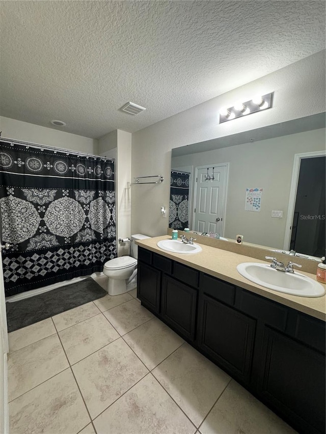 bathroom featuring tile patterned flooring, vanity, a textured ceiling, and toilet