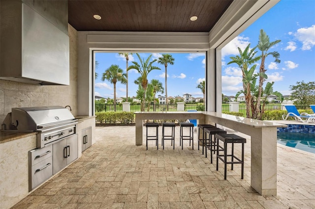 view of patio / terrace with a fenced in pool, an outdoor bar, exterior kitchen, and a grill