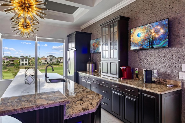 kitchen with sink, a healthy amount of sunlight, stainless steel fridge, a chandelier, and a center island with sink