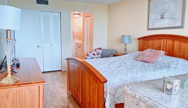 bedroom with light hardwood / wood-style floors, a closet, and ensuite bathroom