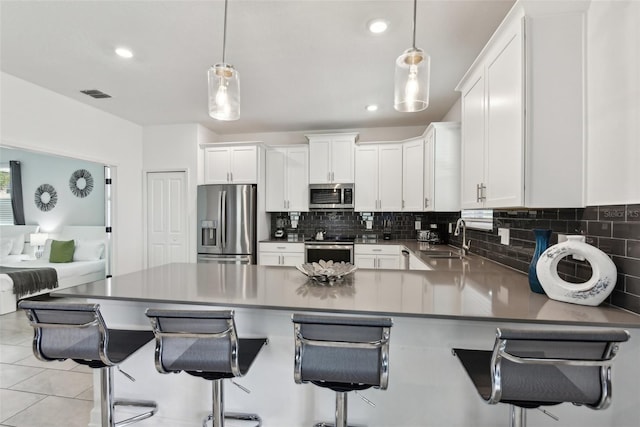 kitchen featuring appliances with stainless steel finishes, white cabinetry, and hanging light fixtures