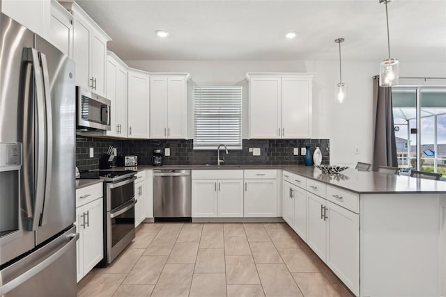 kitchen featuring light tile patterned flooring, white cabinetry, hanging light fixtures, and appliances with stainless steel finishes