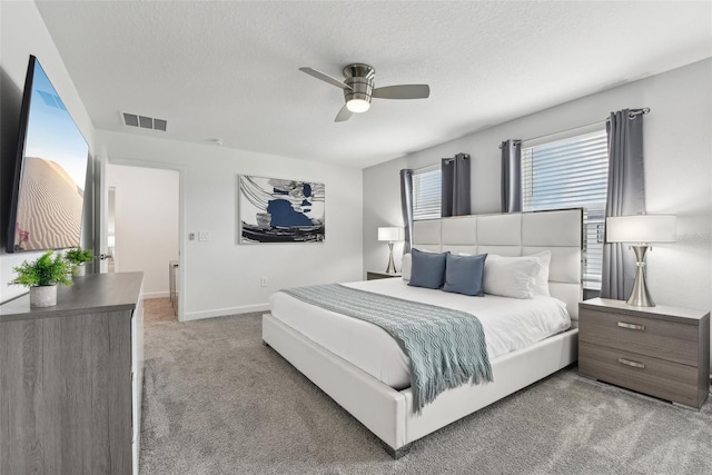 bedroom featuring ceiling fan, light colored carpet, and a textured ceiling