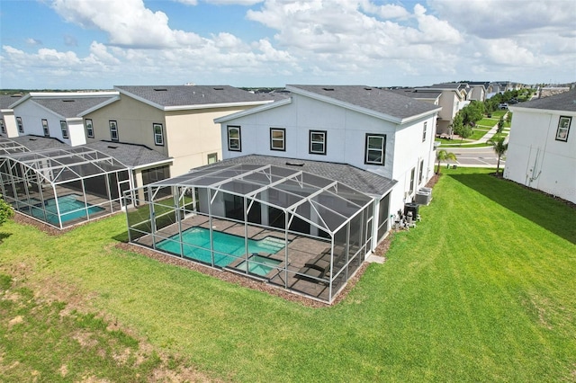 back of property featuring glass enclosure, a patio area, and a lawn