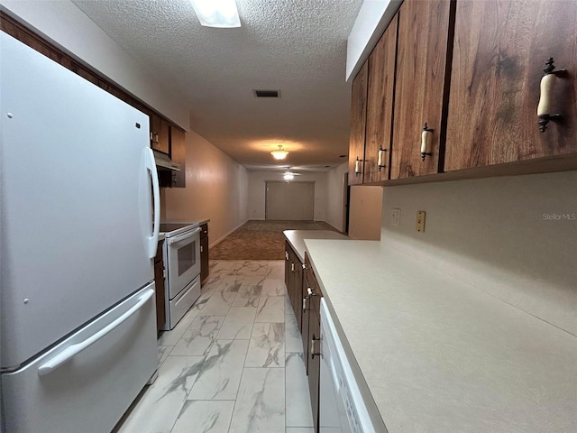 kitchen featuring a textured ceiling and white appliances