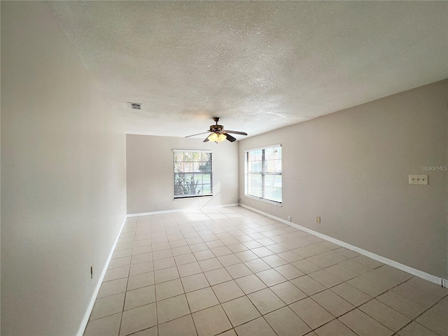 empty room with ceiling fan, light tile patterned flooring, and a textured ceiling