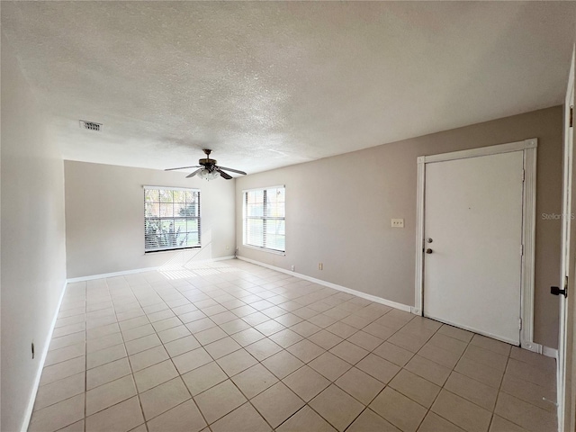 spare room with ceiling fan, light tile patterned flooring, and a textured ceiling